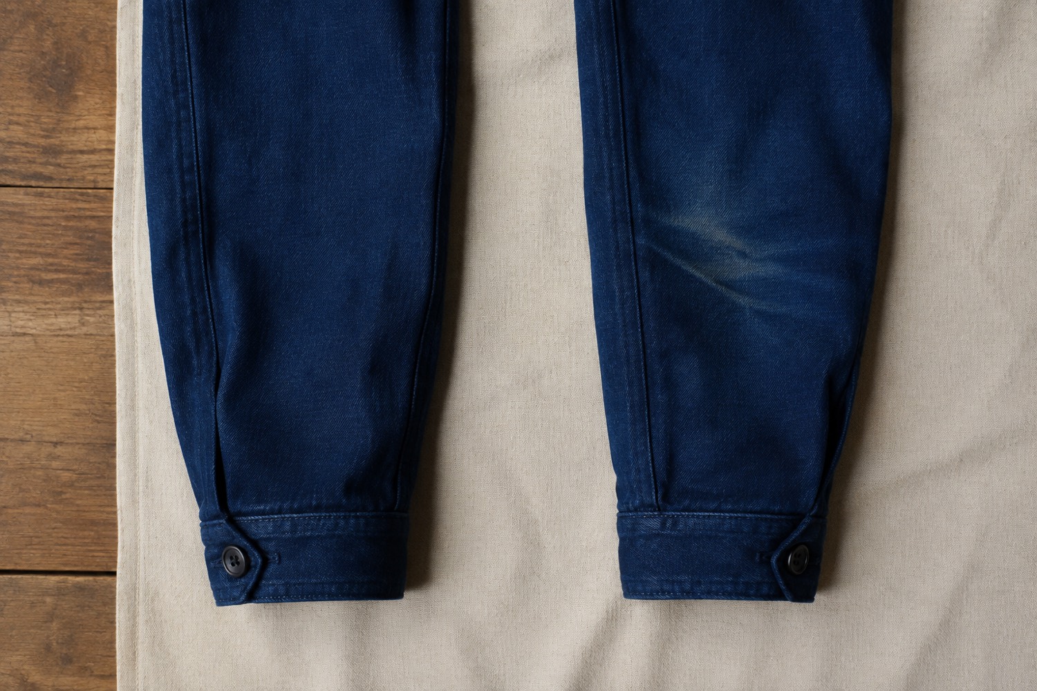 Two identical indigo canvas sleeves side by side, the right one lightened along the elbow fold and visibly softened.